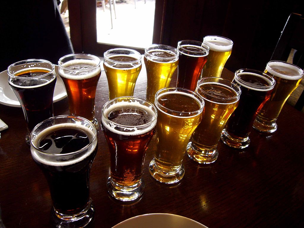 A selection of light and dark beers in glasses on a wooden table