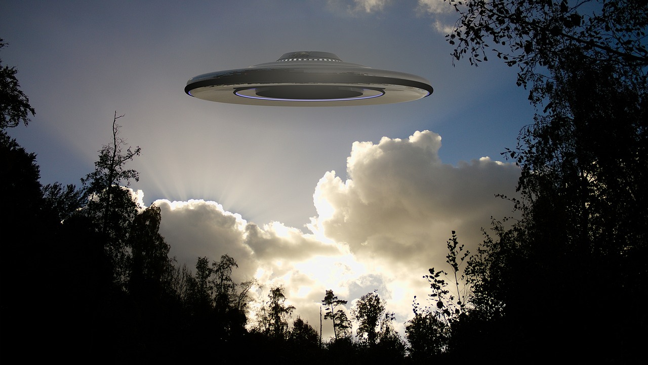 a spaceship in cloudy skies over a forest during daytime