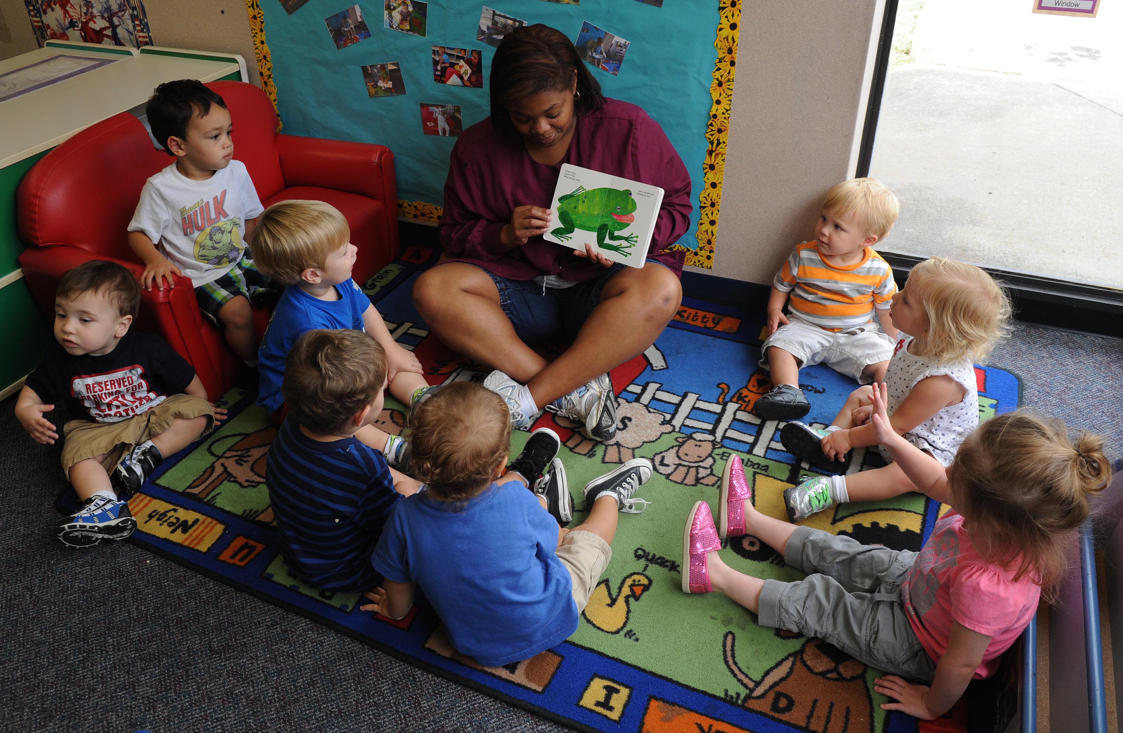 a woman reads a picture book to small children