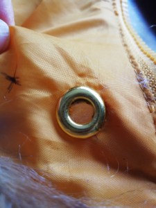 A finished eyelet sitting on top of yellow fabric.