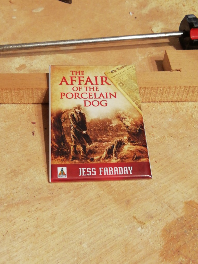 A refrigerator magnet with the cover of The Affair of the Porcelain Dog by Jess Faraday.
