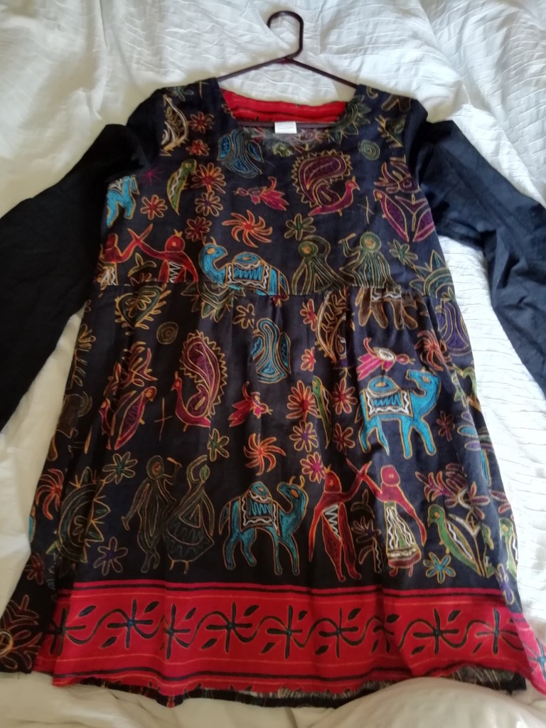 A long sleeved dark blue tunic top with multicolored pictures of camels, people, and birds.