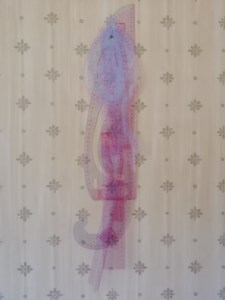 An assortment of clear plastic rulers hanging from a nail on a wall.