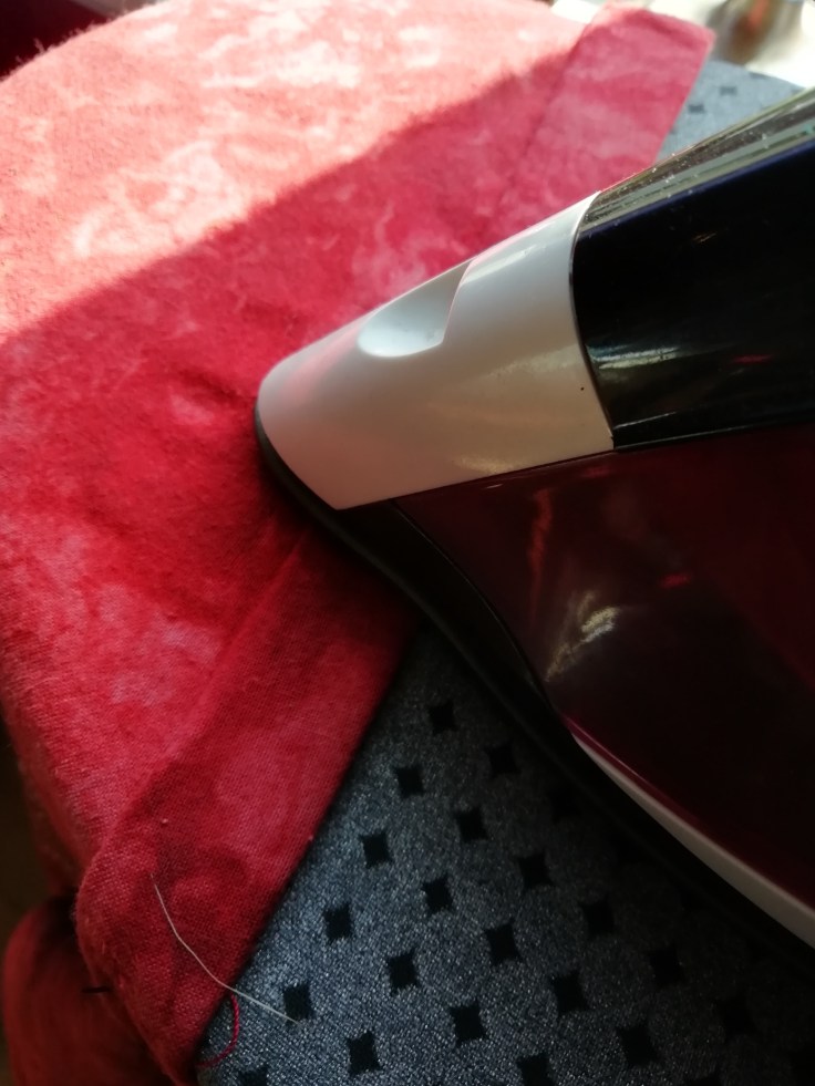Pressing the rolled sleeve hem with an iron.